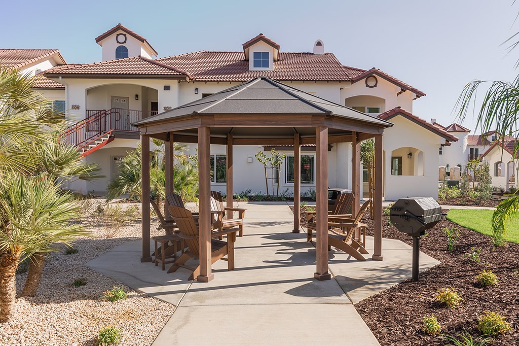 A gazebo is in the middle of a patio with chairs around it.