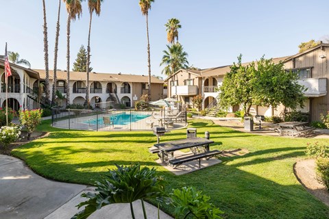 A pool surrounded by a fence and a bench in the foreground.