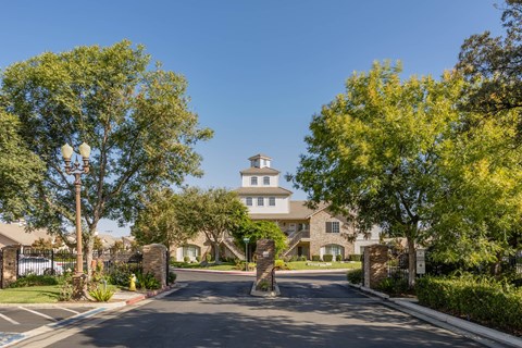 A gated entrance to a large house with a driveway in between.