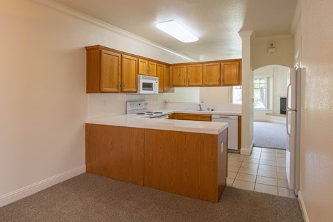 A kitchen with white countertops and wooden cabinets.