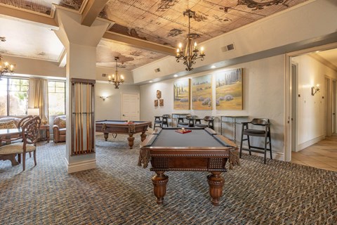 A room with a pool table and a painting of a landscape on the wall.