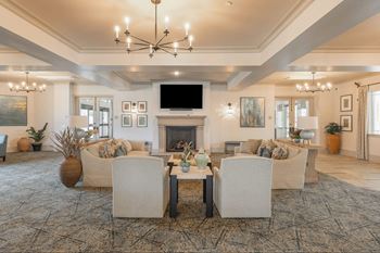 A living room with a fireplace and a large chandelier.at The Villas at Ellis Manor, Fresno California