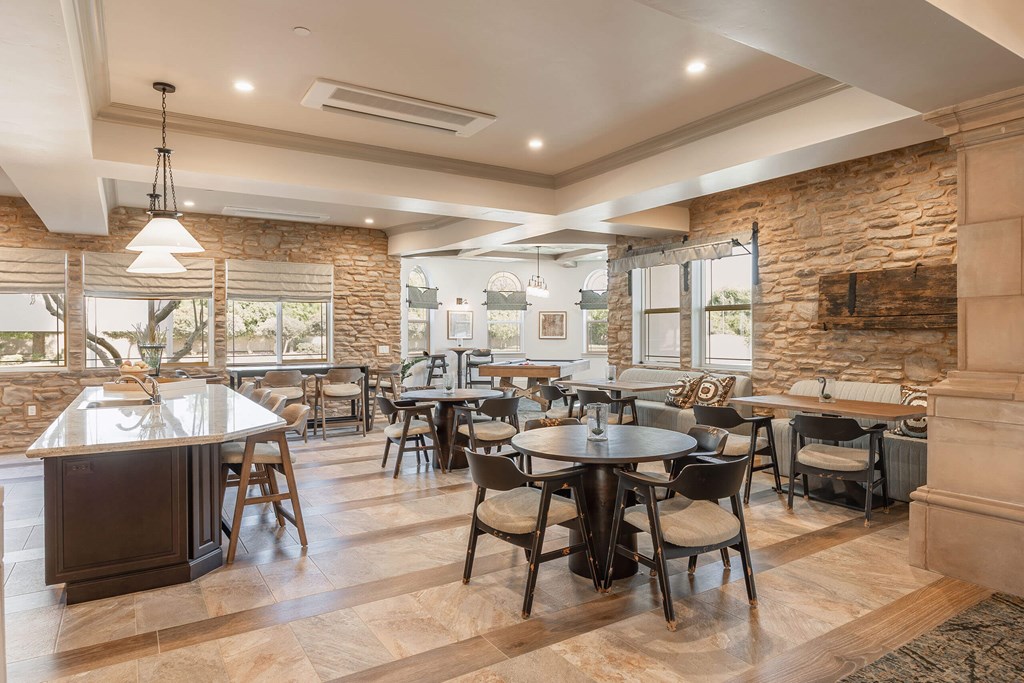 A modern dining room with a stone wall and a large island.at The Villas at Ellis Manor, California