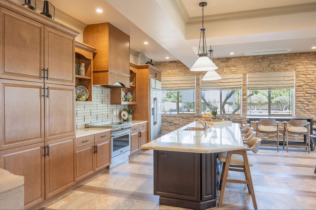A kitchen with wooden cabinets and a stone wall.at The Villas at Ellis Manor, Fresno, CA 93720