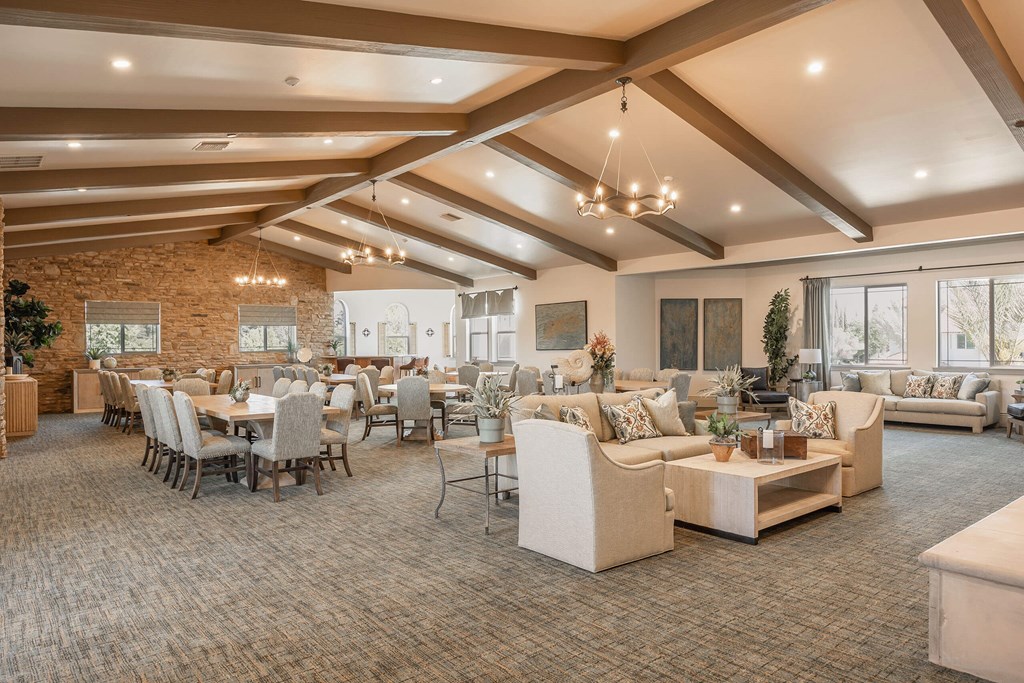 A spacious living room with a stone wall and a large window.at The Villas at Ellis Manor, Fresno