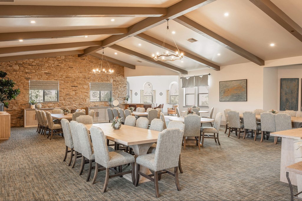 A room with tables and chairs and a stone wall.at The Villas at Ellis Manor, Fresno, CA