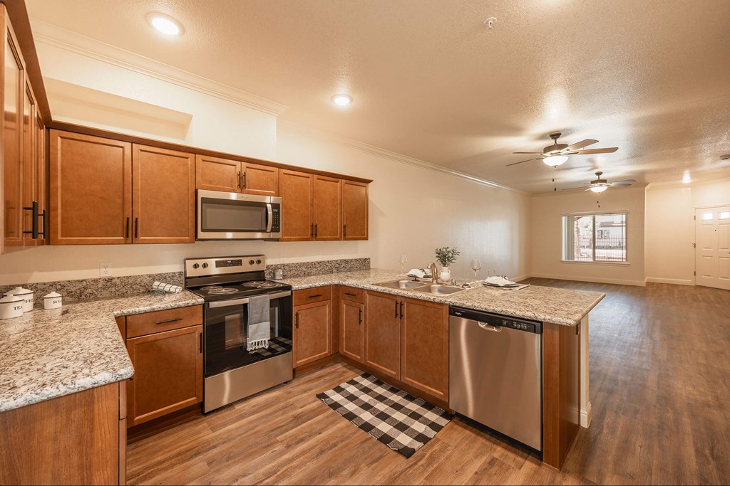 A kitchen with wooden cabinets and a checkered mat on the floor.at The Villas at Ellis Manor, Fresno California