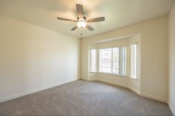A room with a ceiling fan and carpeted floor.at The Villas at Ellis Manor, Fresno