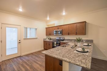 A kitchen with a granite countertop and wooden cabinets.at The Villas at Ellis Manor, Fresno, CA 93720