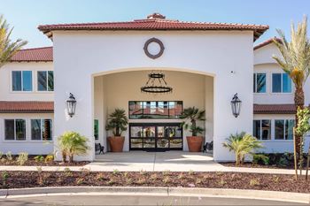 A white building with a red tile roof and a circular emblem above the entrance.at The Villas at Ellis Manor, Fresno, 93720 