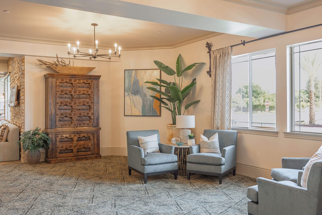 A living room with a grey sofa, a wooden cabinet, and a painting on the wall.at The Villas at Ellis Manor, Fresno, CA
