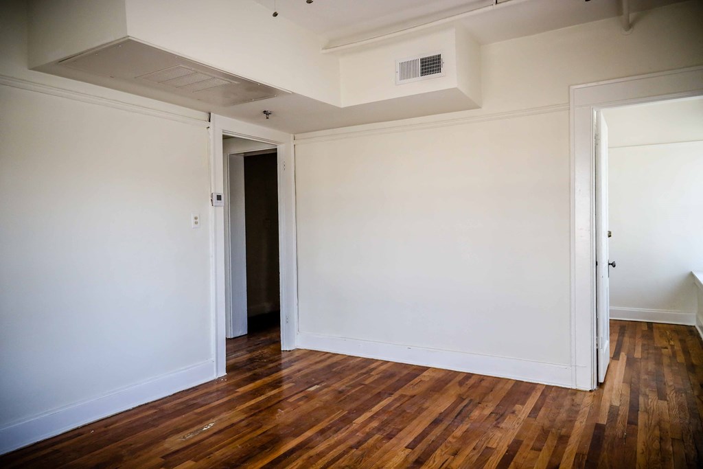 an empty room with white walls and wood floors