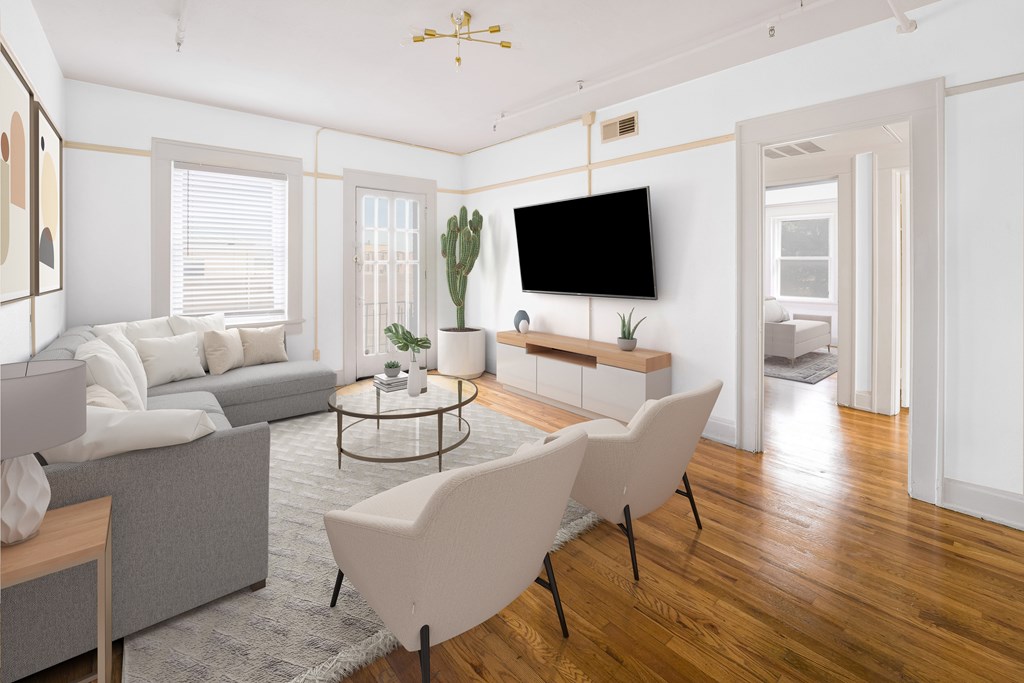 A living room with a grey couch, a white chair, and a black television.