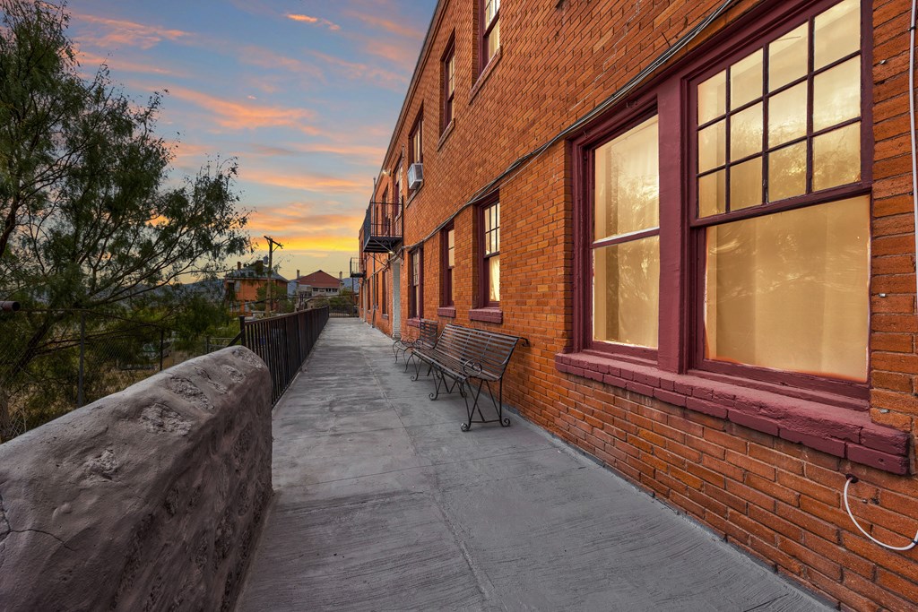 A brick building with a bench on the sidewalk.