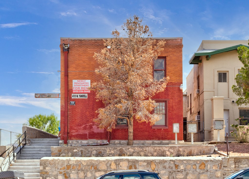 a red brick building with stairs and a tree in front of it
