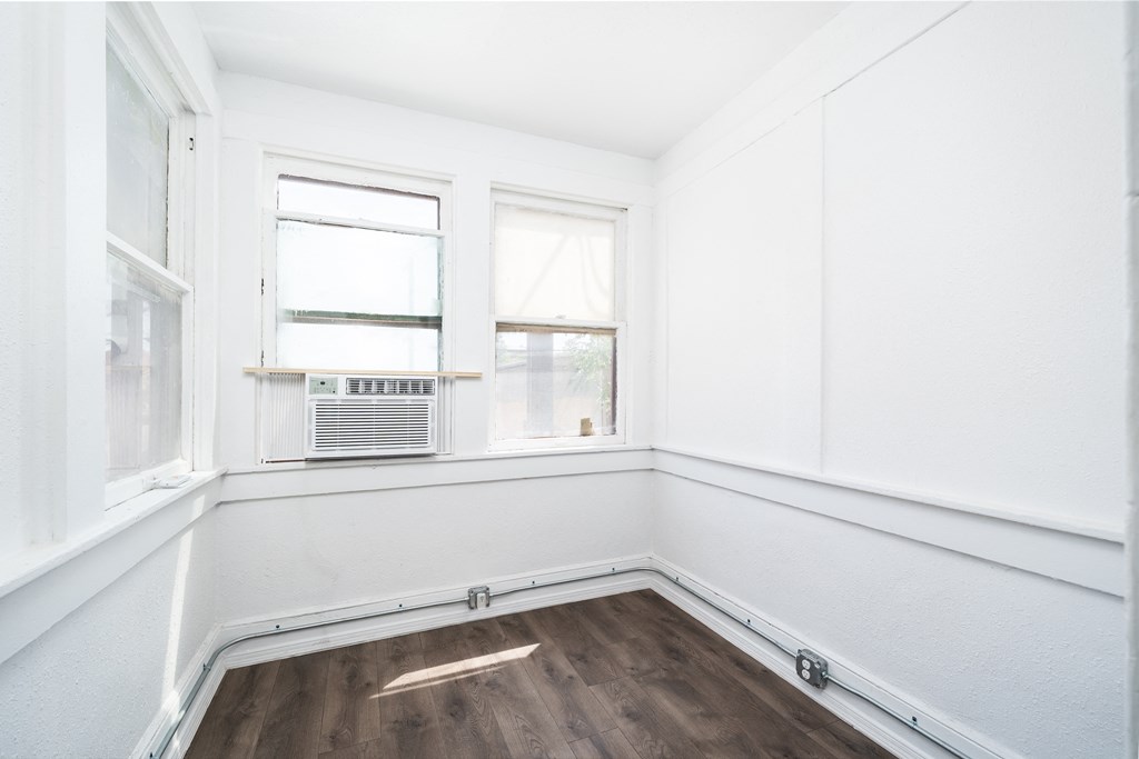 an empty room with a radiator and two windows