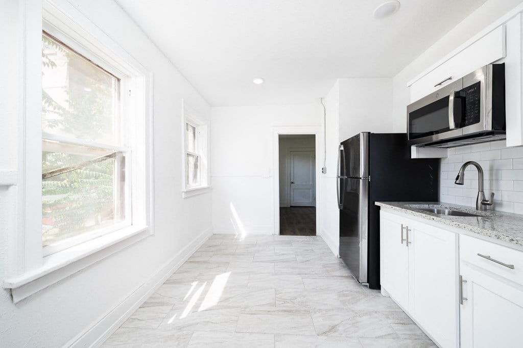 a kitchen with white cabinets and black appliances and a window