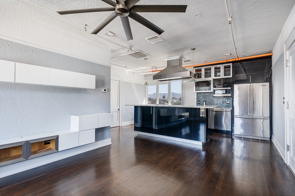 A modern kitchen with a black countertop and stainless steel appliances.