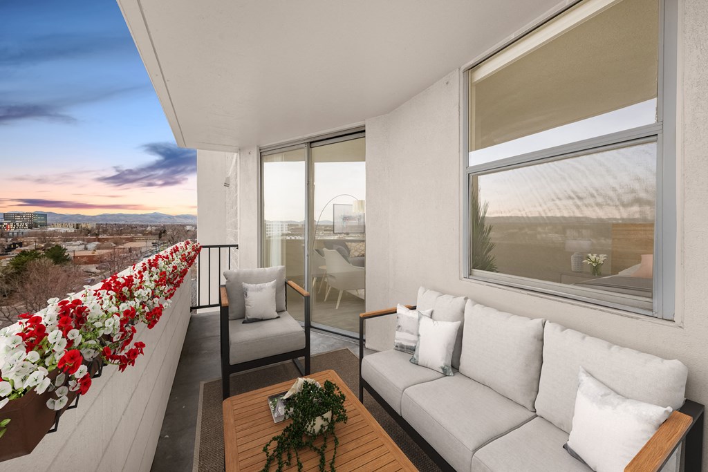a living room with a couch and a balcony with a view of the city