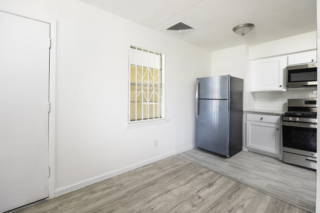 an empty kitchen with stainless steel appliances and a window