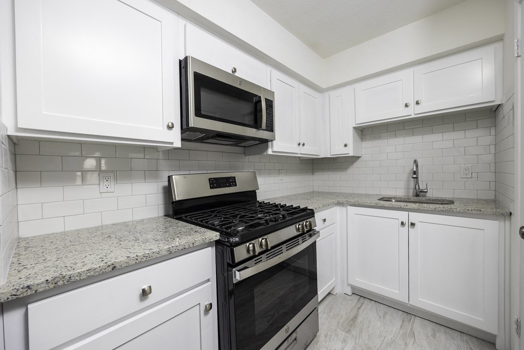 a kitchen with white cabinets and a stove and a microwave