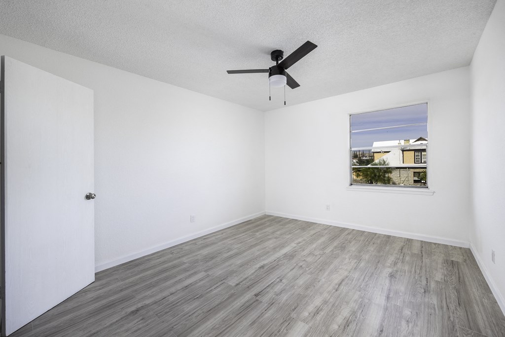 an empty room with white walls and a ceiling fan