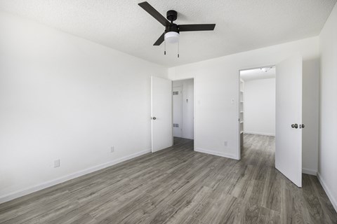 an empty living room with white walls and a ceiling fan