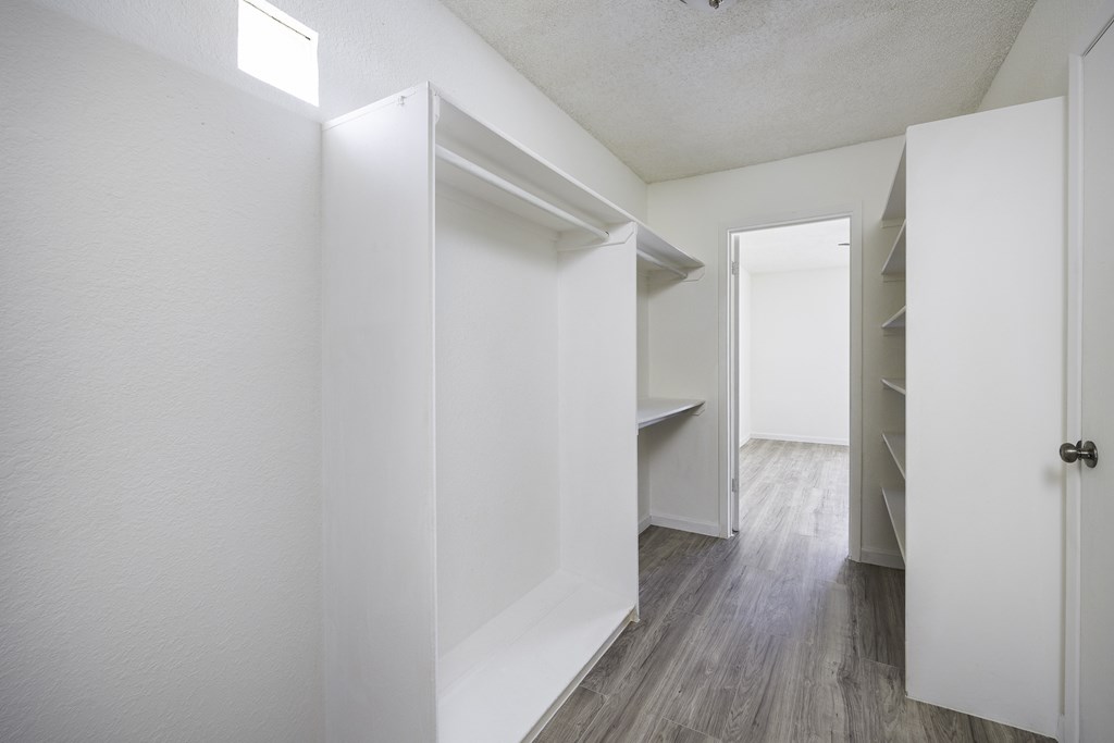 an empty room with white closets and a wood floor