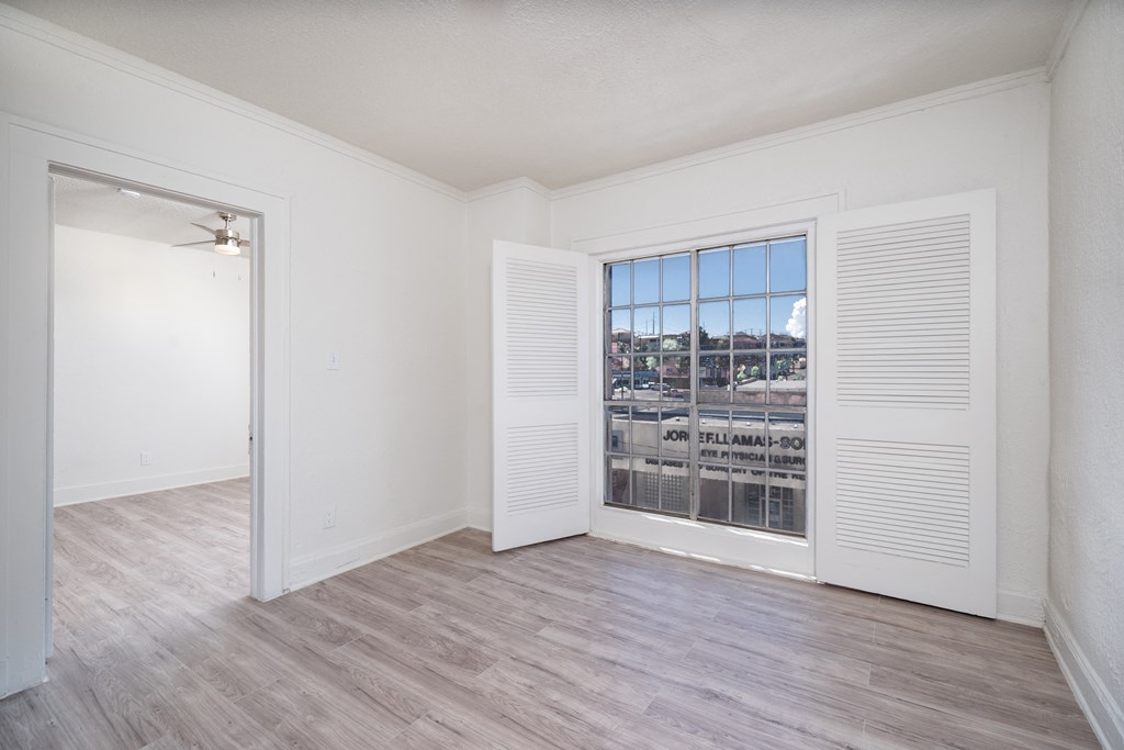 an empty living room with a large window and white walls