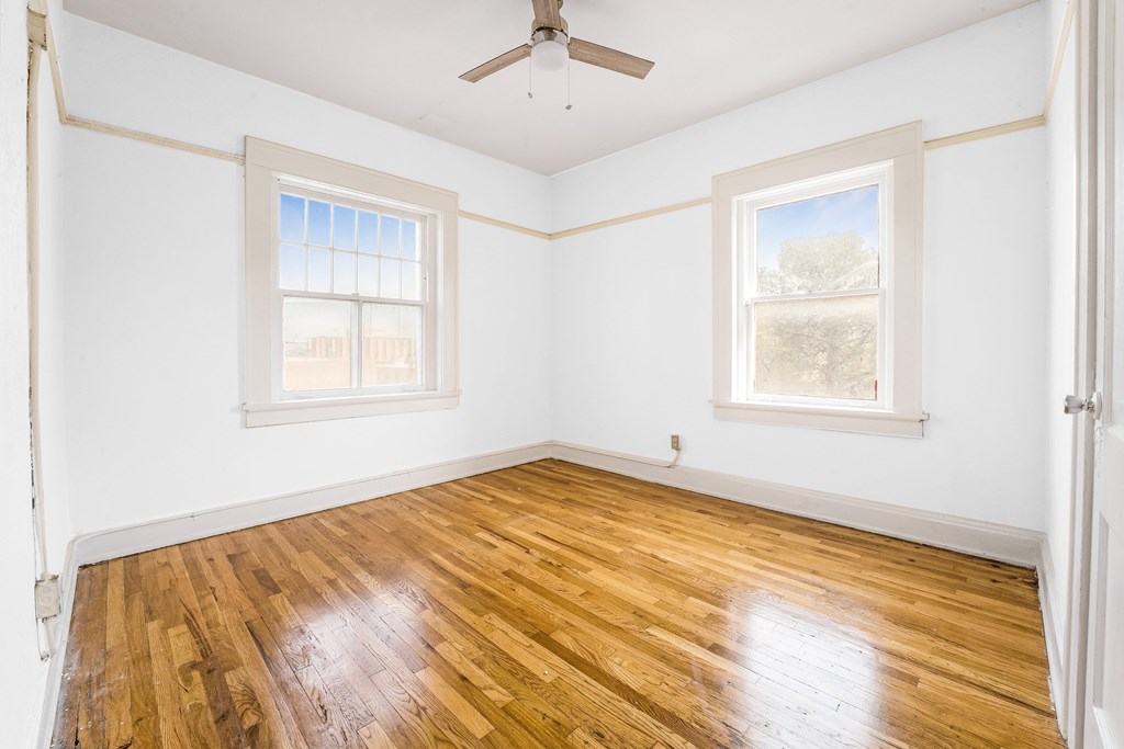 A room with wooden floors and two windows.