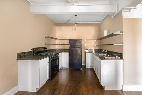 A kitchen with a black refrigerator and white cabinets.