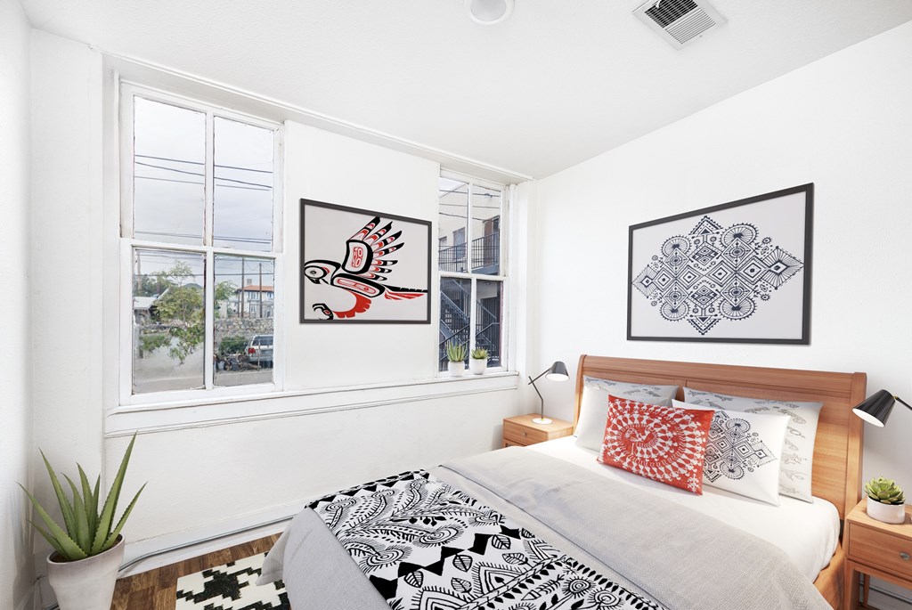 A bedroom with a bed, two pillows, a nightstand, and two framed pictures on the wall.