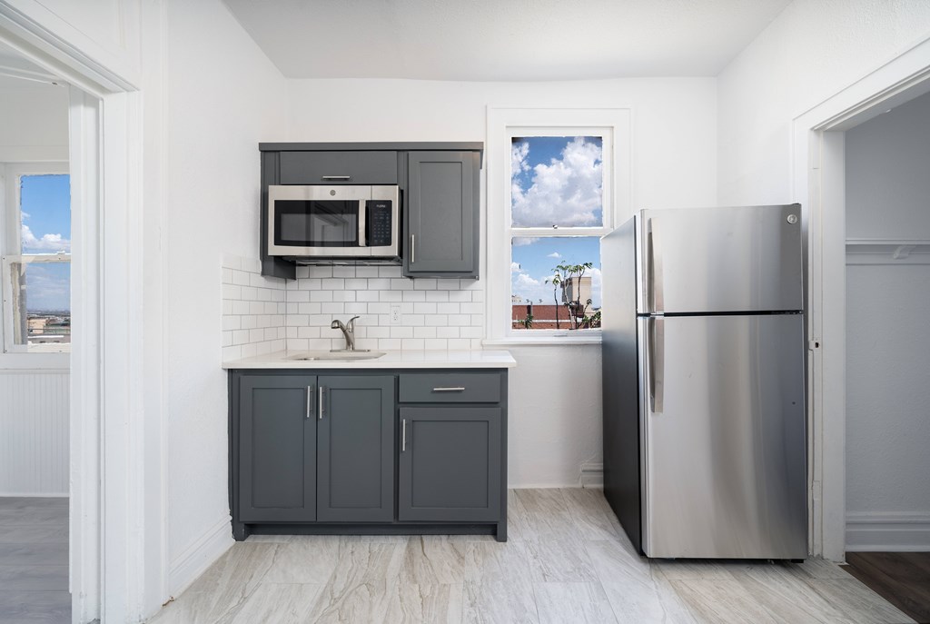 A kitchen with a stainless steel refrigerator and a white tiled backsplash.
