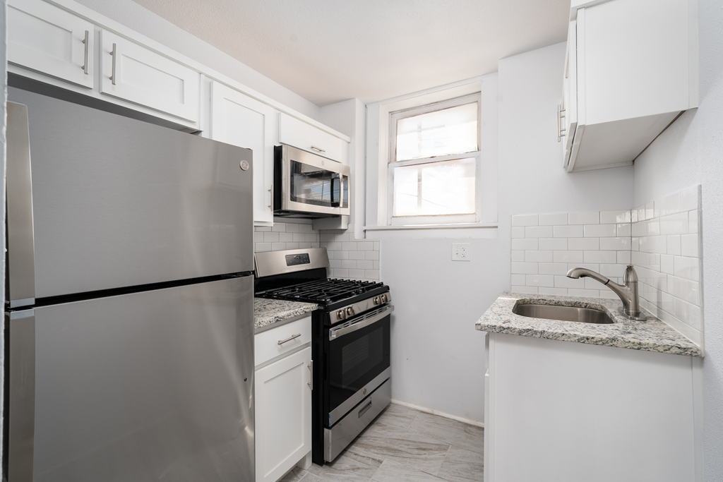 a kitchen with white cabinets and black appliances and a sink
