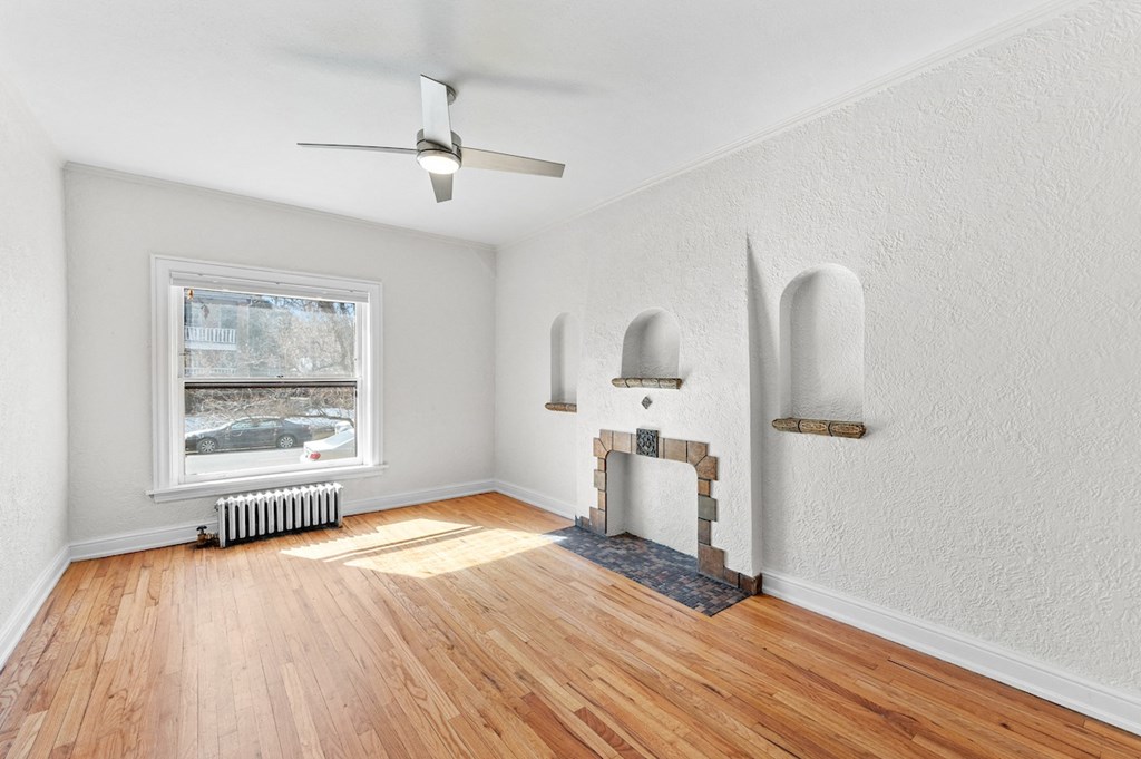 an empty living room with a fireplace and wood floors