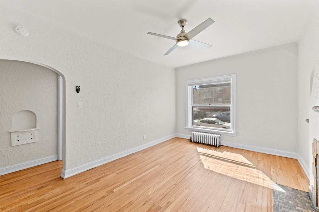 an empty living room with wood floors and a ceiling fan