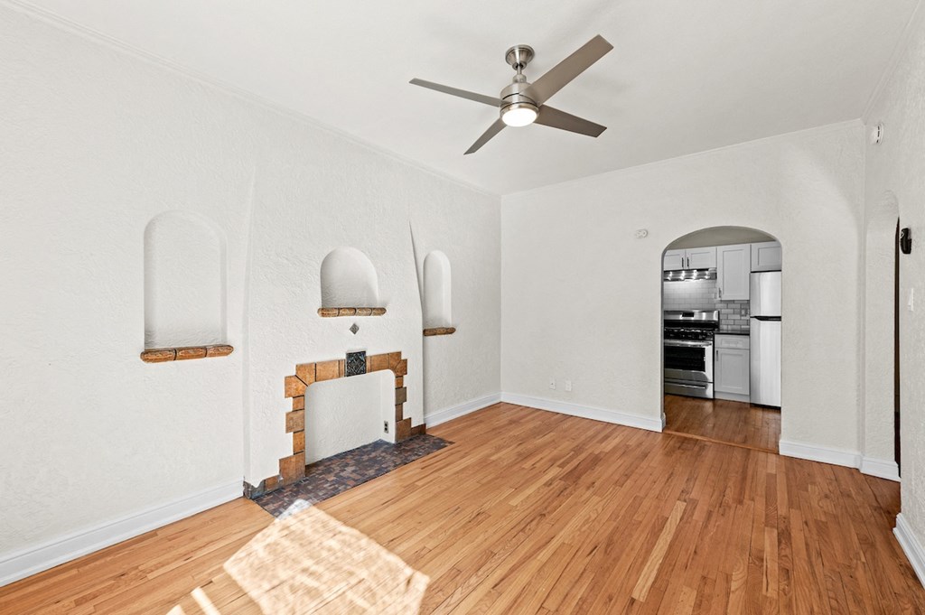 an empty living room with a fireplace and a ceiling fan