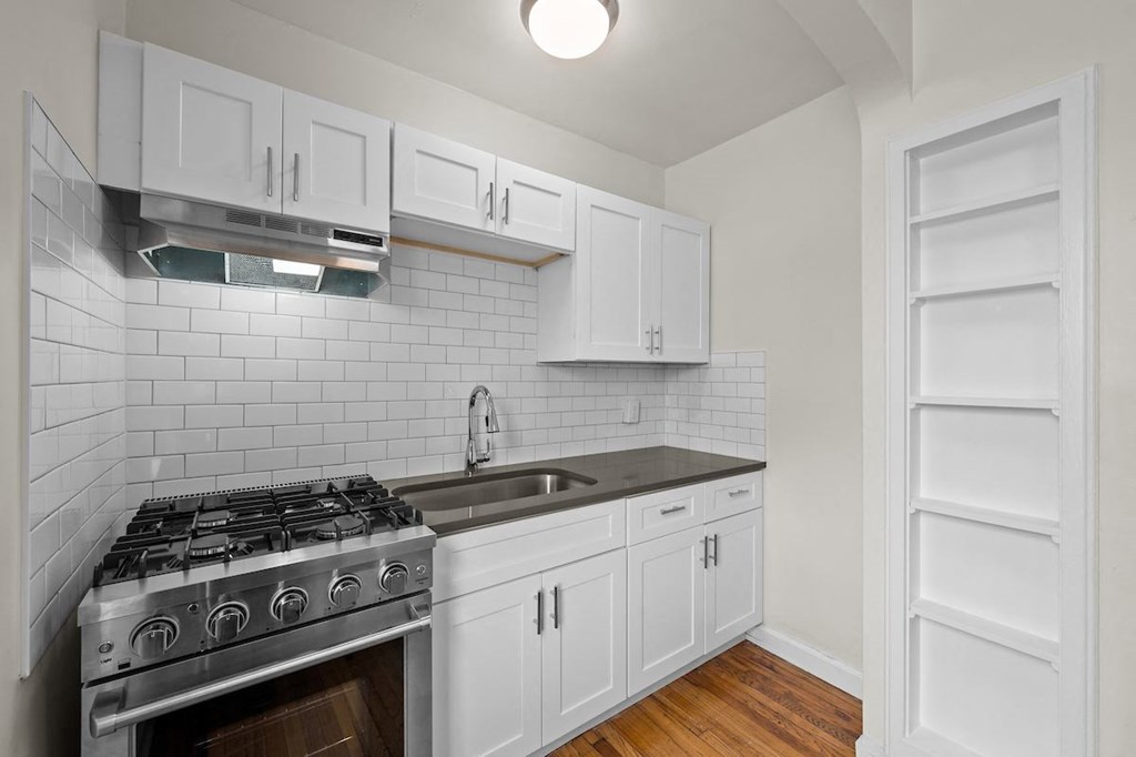 a kitchen with white cabinets and a stove and a sink