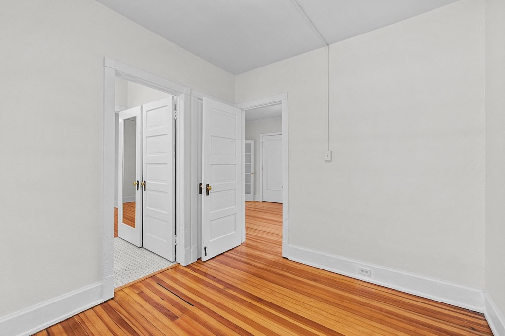 an empty room with wooden floors and white walls