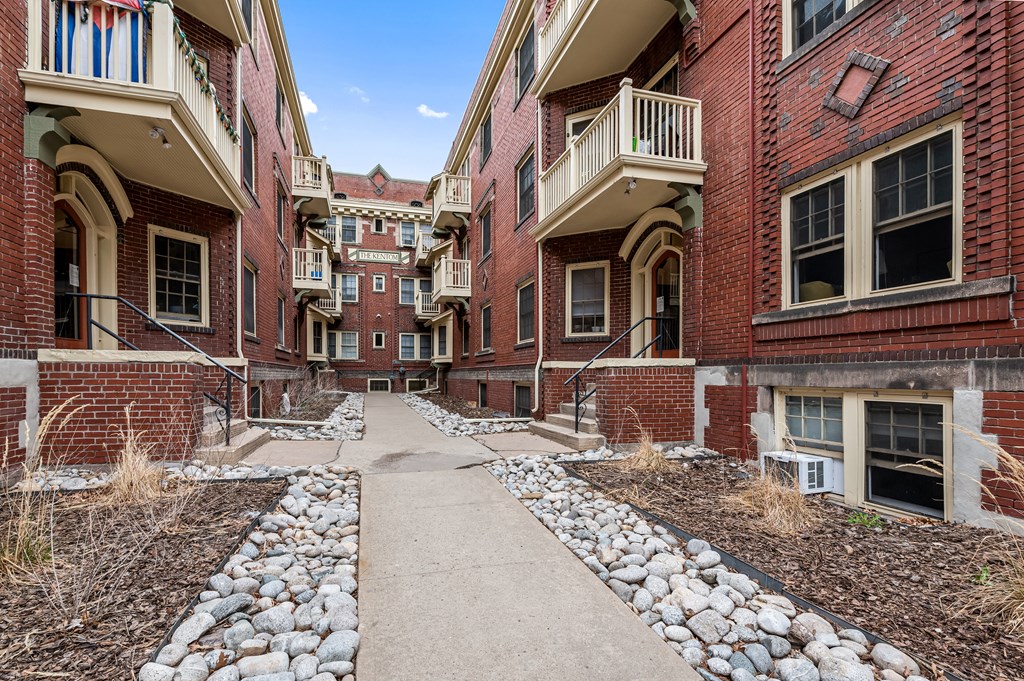 an empty walkway between two buildings with rocks and dirt