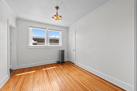 an empty living room with wood floors and a window