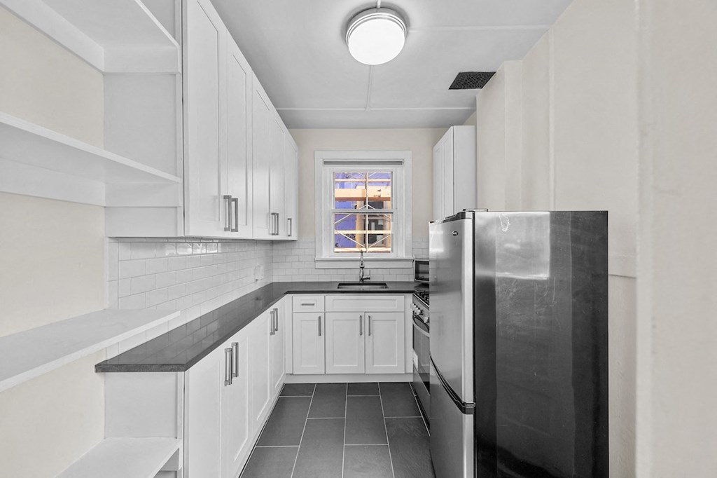 a kitchen with white cabinets and a stainless steel refrigerator