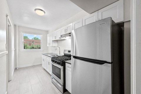 a white kitchen with a stainless steel refrigerator