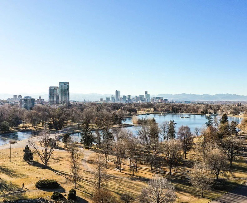 a park with a lake and a city in the background