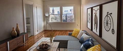 A living room with a grey couch and a bicycle picture on the wall.