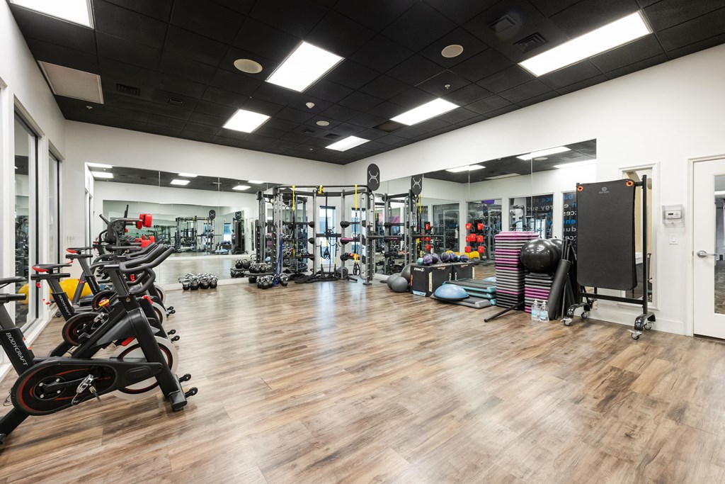 a gym with cardio equipment and weights on a wooden floor