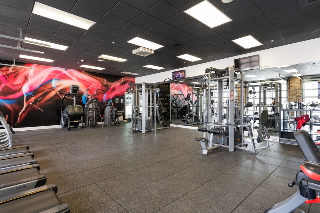 a gym with cardio equipment and a mural on the wall