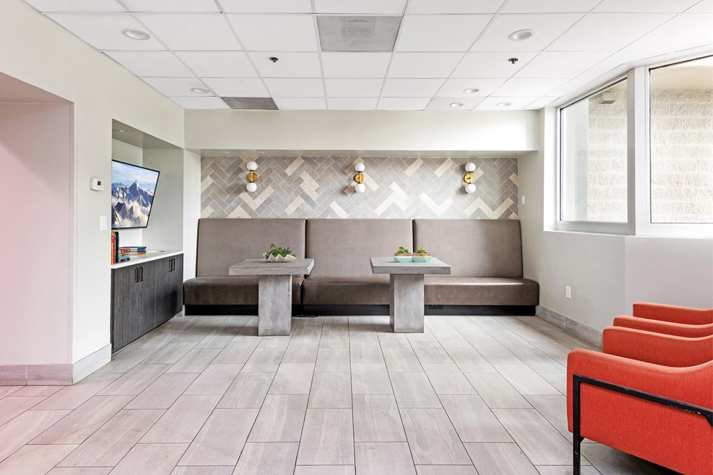a lobby with couches and tables in front of a tv