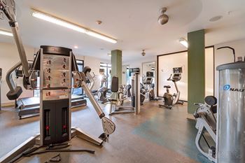 A gym with a variety of equipment including treadmills, weights, and exercise machines.