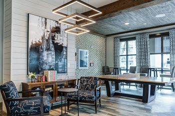 A modern dining room with a large painting on the wall and a wooden table surrounded by chairs.